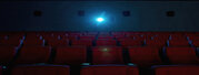 Interior of movie theater with empty red seats and projector